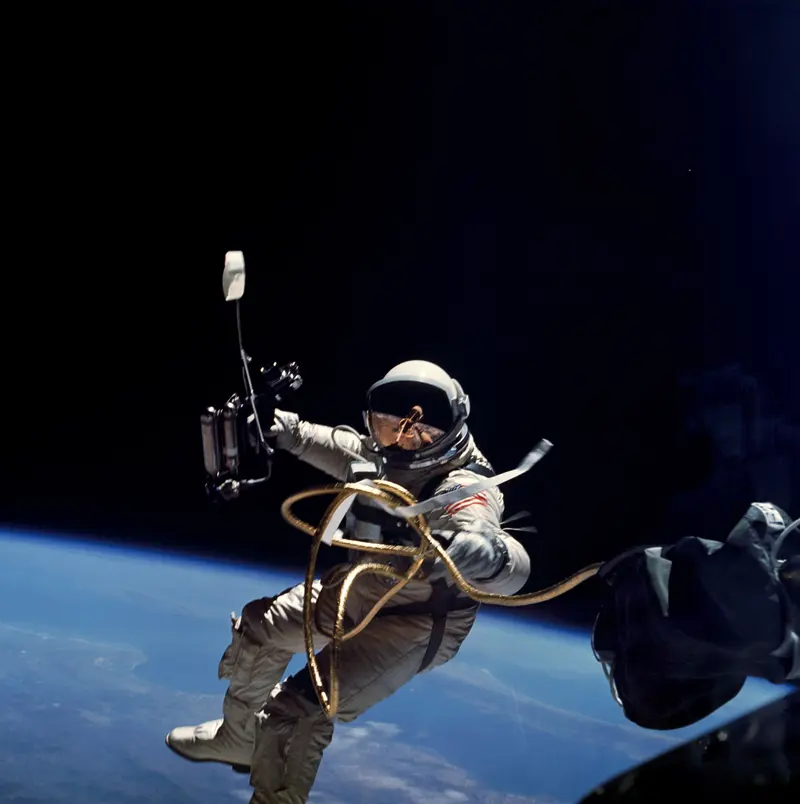 First American Spacewalk. Ed White steps out of Gemini 4 and floats above the Earth for 23 minutes, tethered by a gold-wrapped cord.