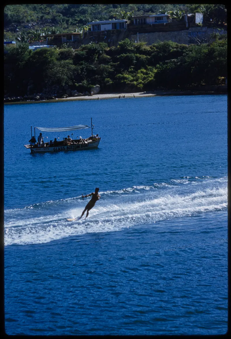 Acapulco Wake, 1954 (Toni Frissell). Another frame from Frissell's December 1954 Acapulco shoot: a skier, a speedboat and green hills dropping into deep blue water.