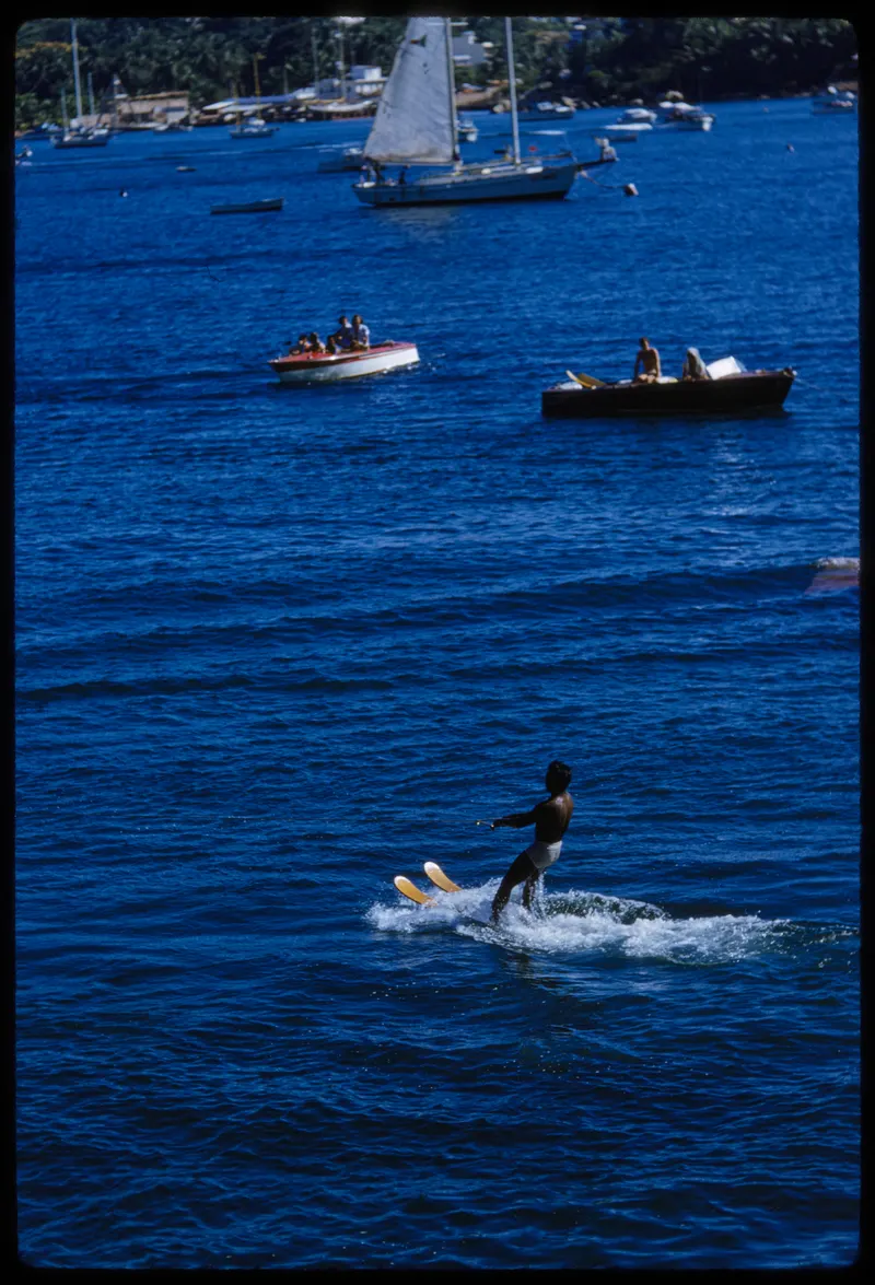 Acapulco Bay, 1954 (Toni Frissell). The bay from above the beach clubs, with a skier and boats crossing it.