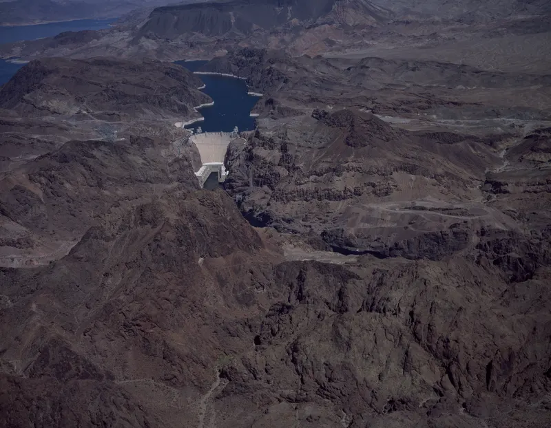 Hoover Dam from the air. Finished two years early in 1935, the dam holds enough concrete to pave a two-lane road from San Francisco to New York; its intake towers are crowned with Art Deco clocks for Nevada and Arizona time.