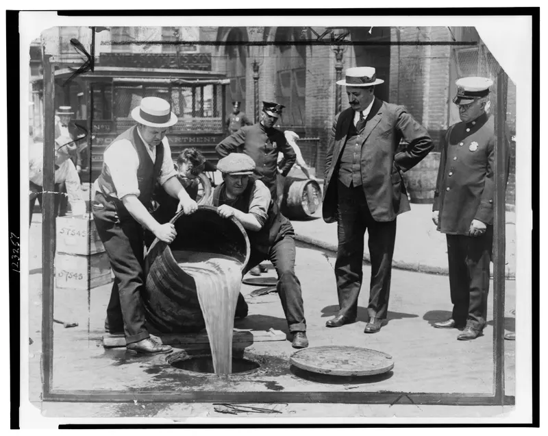 Pouring Liquor into the Sewer, c.1921. NYC Deputy Police Commissioner John Leach watches agents dump seized booze after a raid.